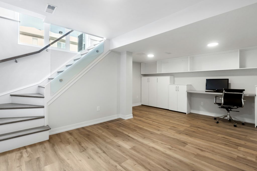 Finished basement remodeling in Cary, NC featuring luxury vinyl flooring, built-in storage, recessed lighting, and a modern multi-purpose living space.