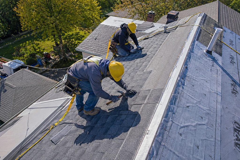 Professional roofing contractors repairing asphalt shingle roof damage on a residential home in Cary, NC.